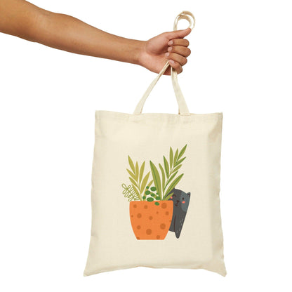 Plant with Cat Peaking from Behind Canvas Tote Bag holding bag